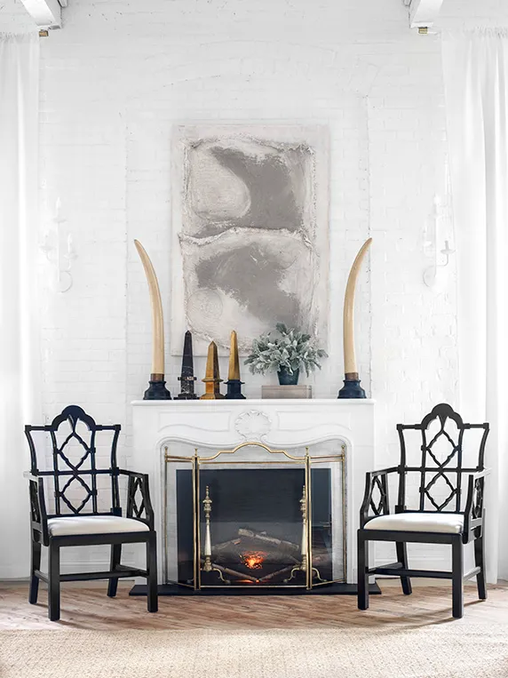 Faux fireplace flanked by black arm chairs