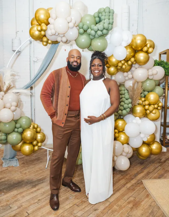 Wedding guests posing in front of a gold tinsel wall and neon sign