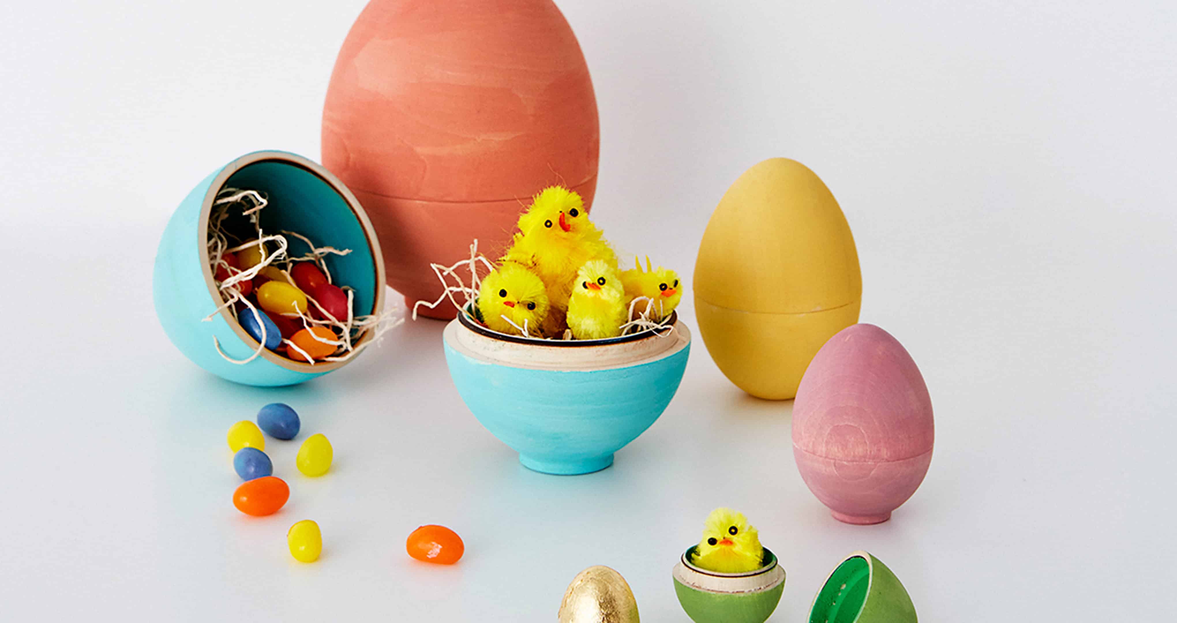 Chick figurines and jelly beans hatching from painted wooden eggs