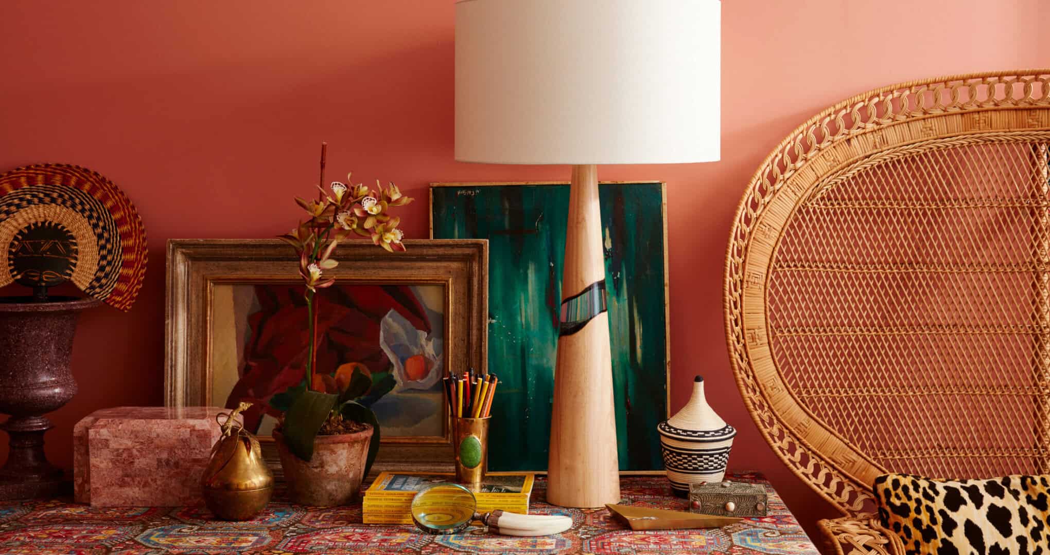 Table lamp vignette with peacock chair against terra cotta painted wall