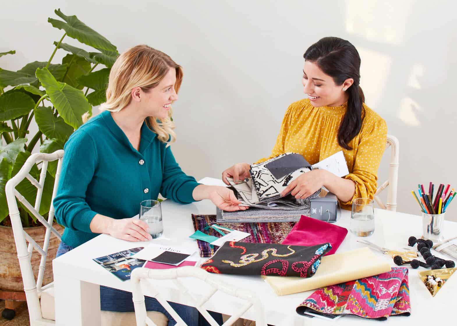 Two female models at a table looking at fabric as though an in-store visit