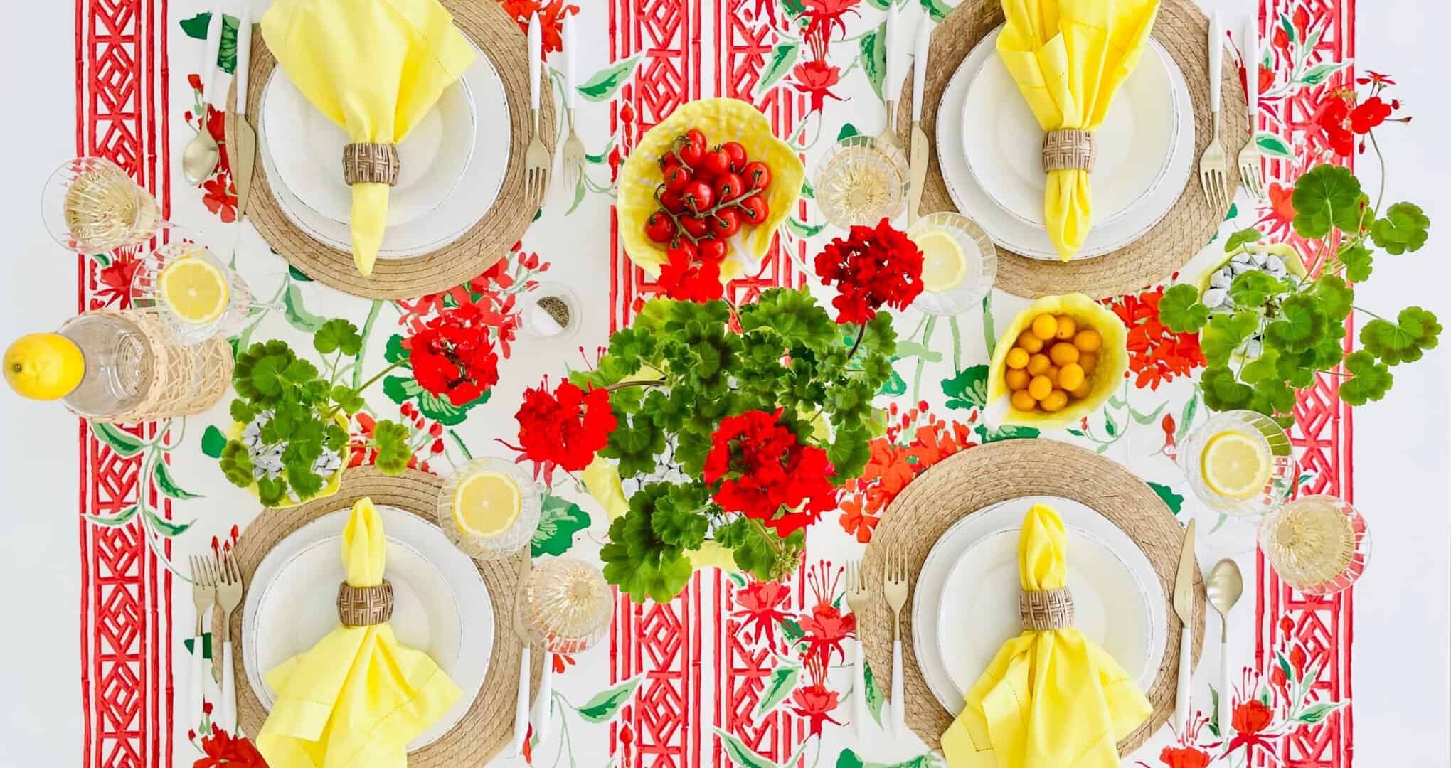 Overhead of table setting with yellow tableware and red geraniums inspired by Positano, Italy