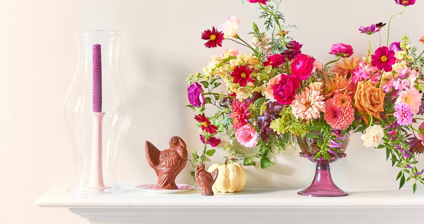 Lush flower arrangement on a mantle with chocolate turkeys for decor