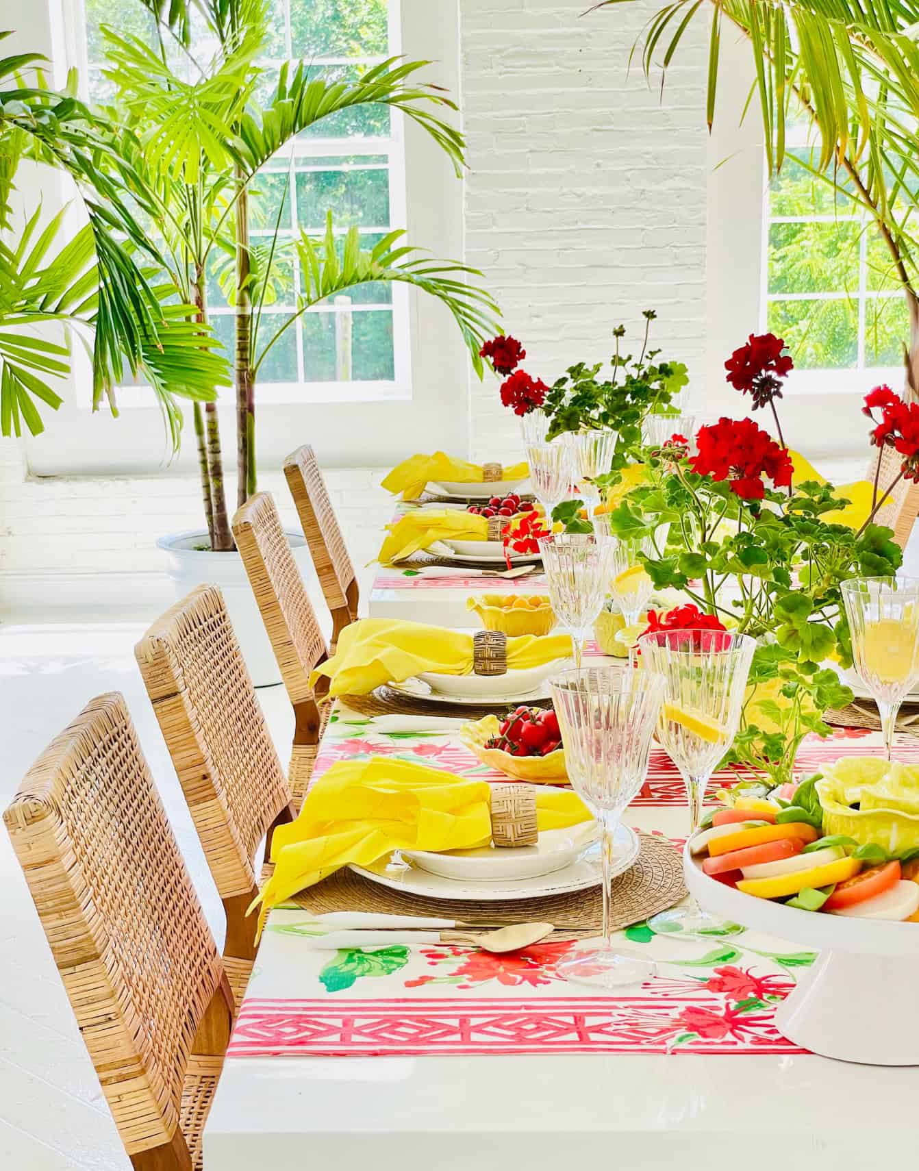 Table setting with yellow tableware and red geraniums inspired by Positano, Italy