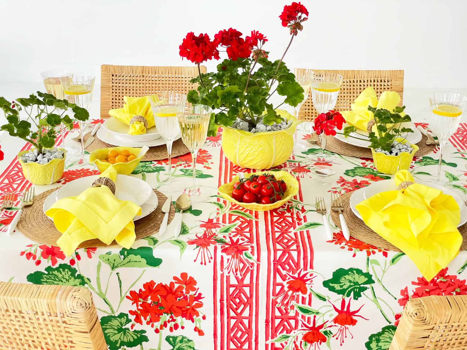 Overall of table with red geranium centerpiece in yellow cabbage ware