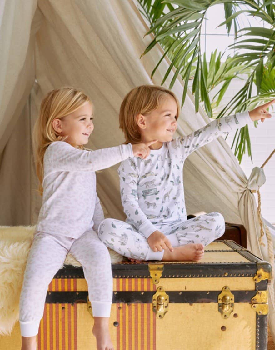 Two young children in a canvas tent wearing printed pajamas