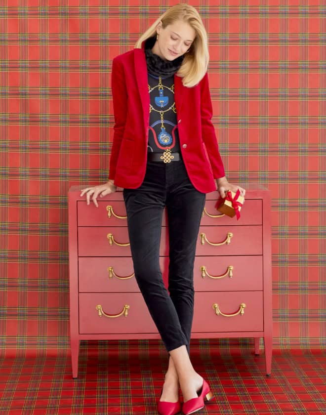 Female model sitting on red dresser against plaid wallpaper