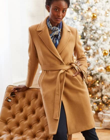 Female model in trench coat with tufted leather chair