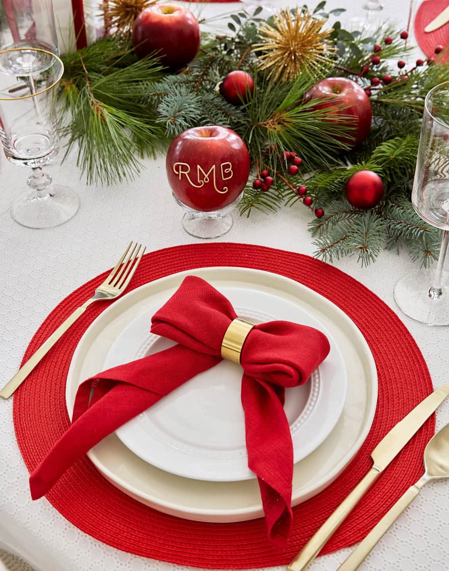 Place setting with napkin tied to look like ribbon and apples for table decor