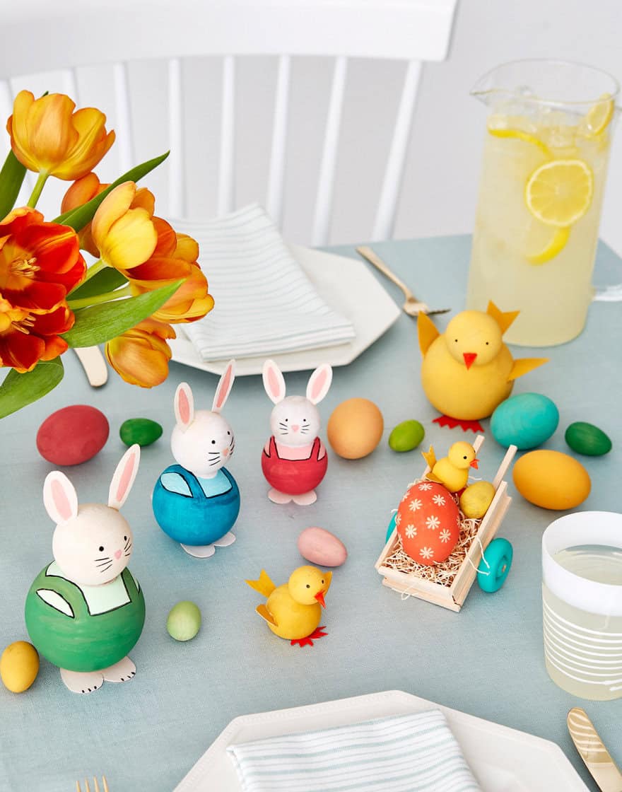 Easter table decorated with figurines of bunnies and chicks made from painted wooden eggs