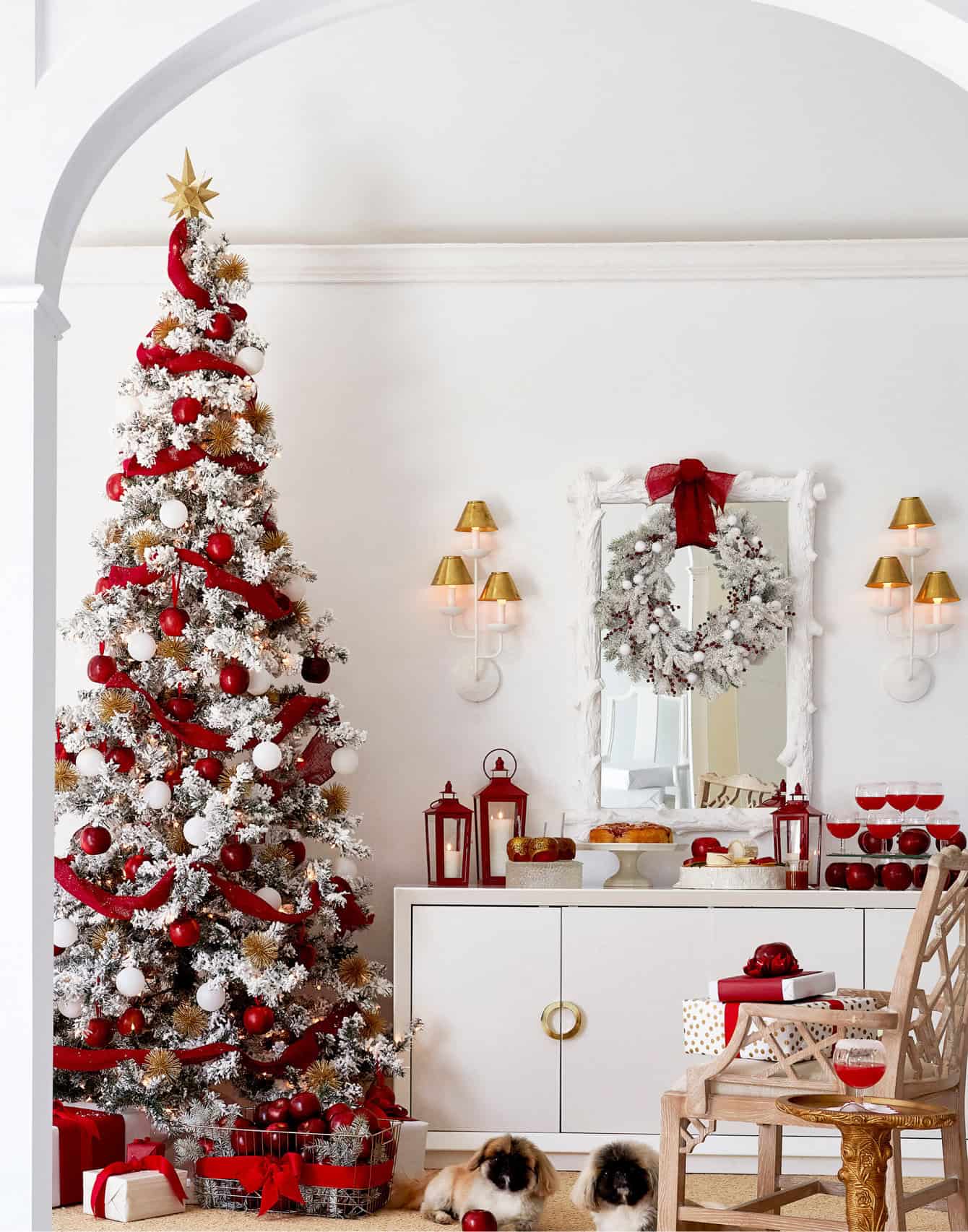 A set with a Christmas tree decorated with apples, sideboard with display of apple desserts and two pups