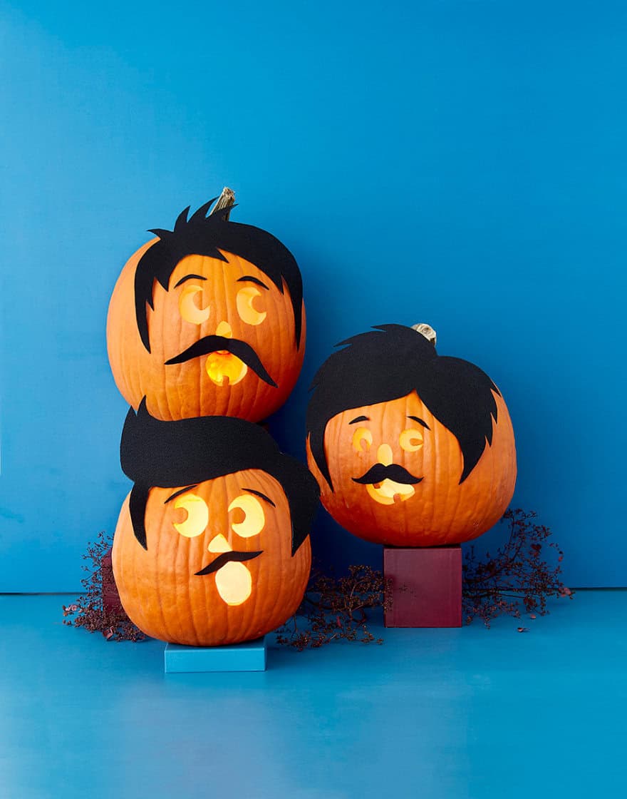 Three orange pumpkins with black hair, mustaches and expressive faces