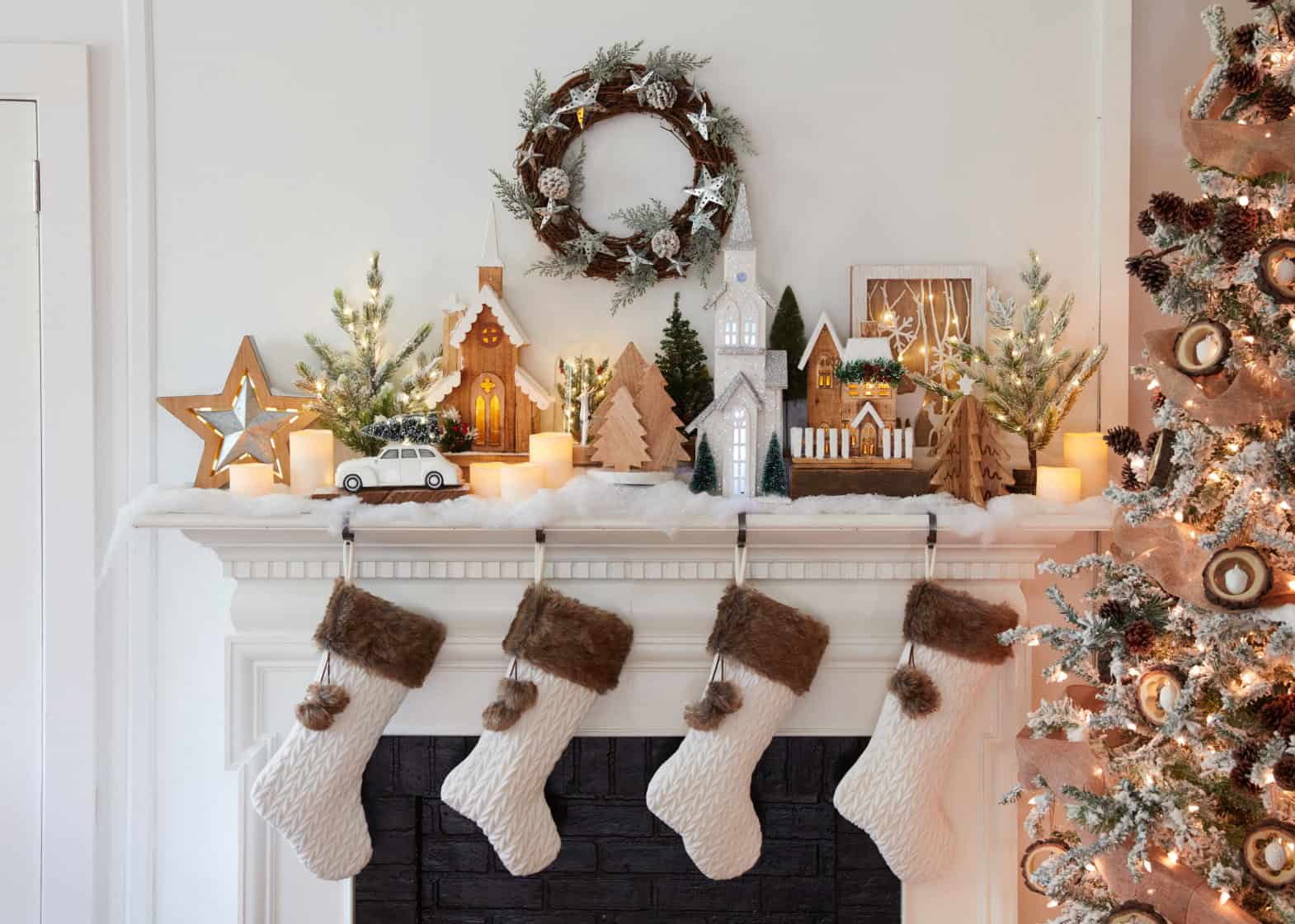 Fireplace mantle decorated with Christmas village and white fur stockings