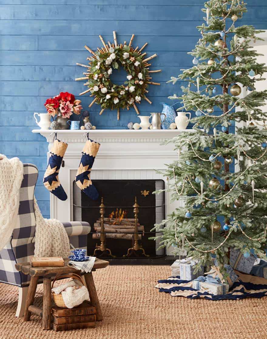 Living room set with blue paneled wall, white fireplace mantle and decorated Christmas tree