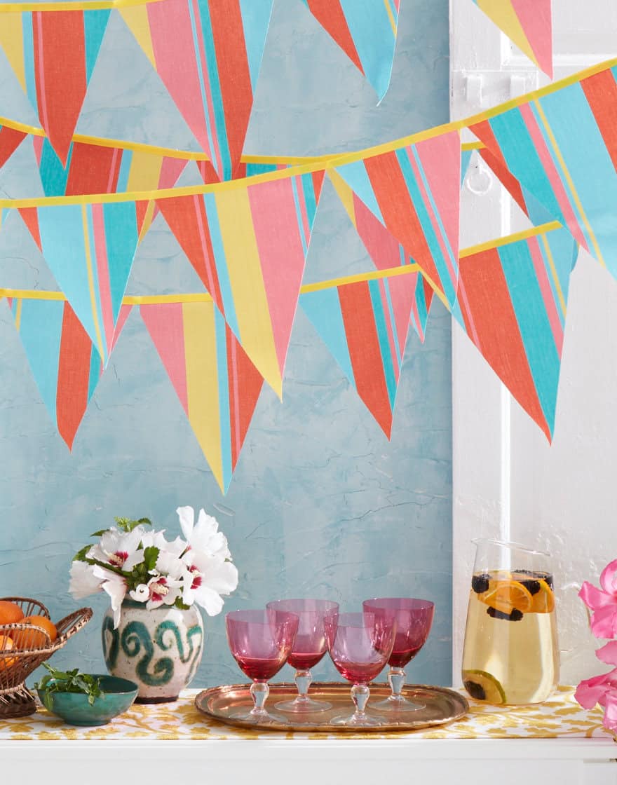 Layers of bunting made from brightly colored striped fabric over a bar setup as though somewhere tropical