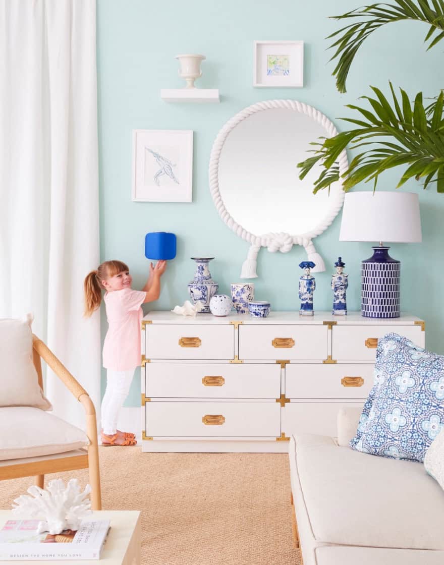 Blue-and-white living room set with young girl sanitizing her hands with product