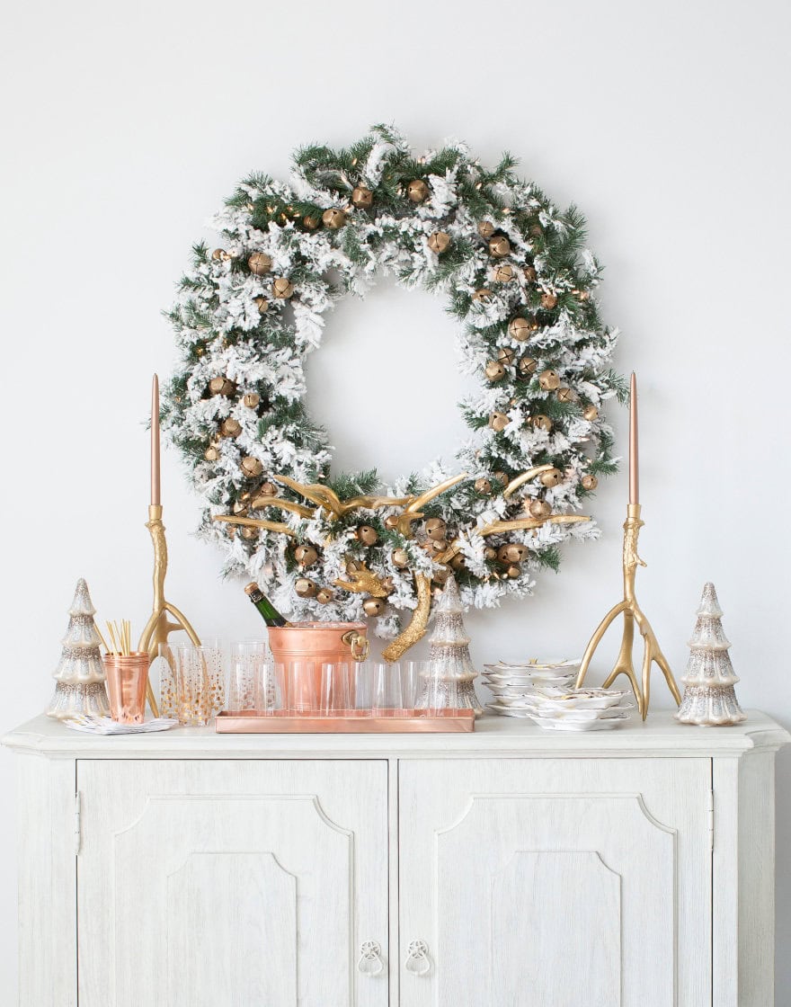 Frosted green wreath hanging over a sideboard with bar display in copper tones