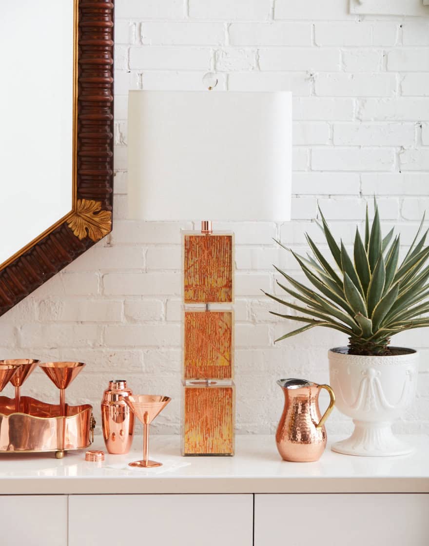 Table lamp vignette with copper tones against white brick