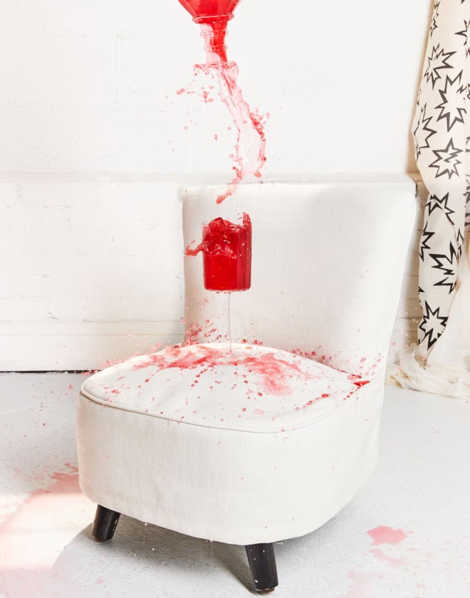 Red wine spilling out of a glass onto a white upholstered chair